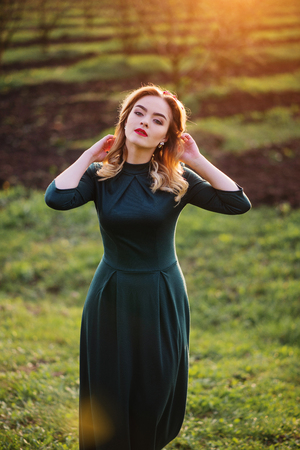 Yong elegance blonde girl at green dress on the garden in spring on sunset.の写真素材