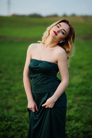 Yong elegance blonde girl at green dress on the garden in spring.の写真素材