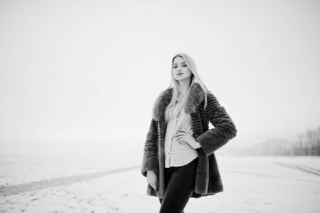 Portrait of young elegance blonde girl in a fur coat background foggy river on winter ice.の写真素材