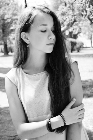 Portrait of beautiful teenage girl in blue blouse, against green of summer park play with her hair.の写真素材
