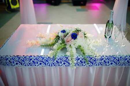 Small table wit bouquet and champagne with glasses on wedding reception.の写真素材