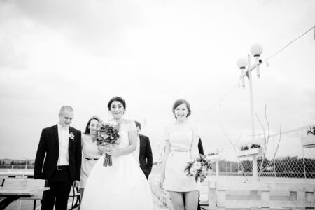 Wedding couple with bridesmaids and best mans stay on the pier berth at cloudy day. Black and white photo.の写真素材