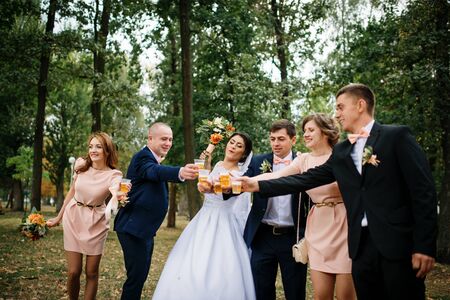 Wedding couple with bridesmaids and best mans drink champagne at park.の写真素材