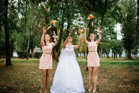 Bride with bridesmaids throw bouquet at wedding day.の写真素材