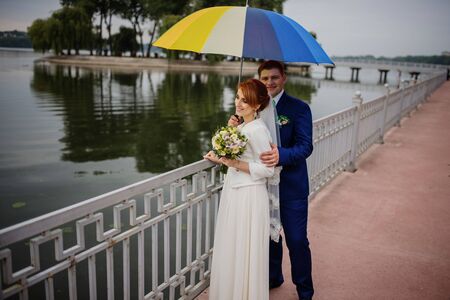 Wedding couple in love under coloured umbrella at rain.の写真素材
