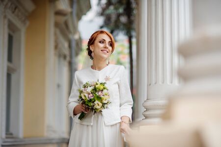 Smiled red haired bride background large columns of antique house.の写真素材