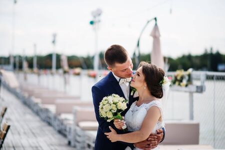 Charming wedding couple hugging on pier of the dock.の写真素材