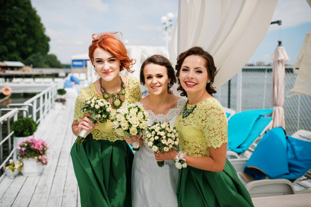 Bride with bridesmaids having fun on pier near lake.の写真素材