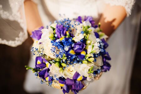 Amazing violet and white wedding bouquet at hands of bridde on sunset.の写真素材