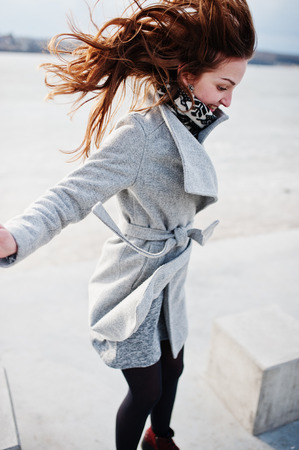 Jumping happy funny model girl on gray coat.の写真素材