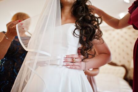 Bridesmaids helped dressed wedding dress for bride at room.の写真素材