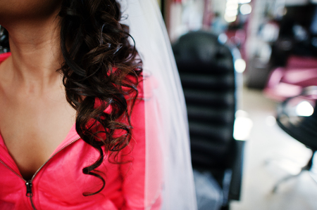 Curly brunette bride sitting on chair at make up studio.の写真素材