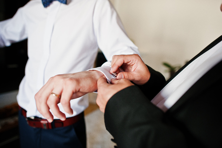 Best man helped stylish groom wear cuff links at wedding day.の写真素材