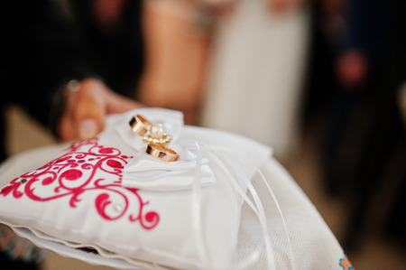 Wedding rings on small pillow at hand of priest on ceremony.