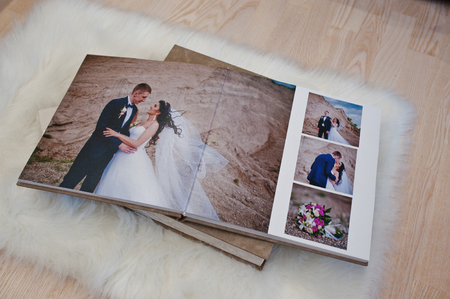 Pages of wedding photobook or wedding album at carpet on wooden background.の写真素材