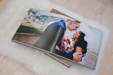Pages of wedding photobook or wedding album at carpet on wooden background.の写真素材