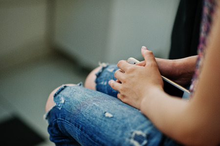 Hand of girl with mobile phone sitting on chair at beauty salon.の写真素材