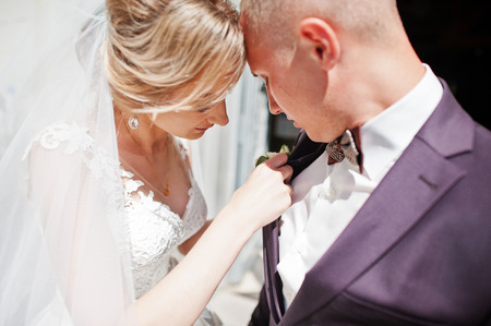 Bride tie buttonhole for her groom at wedding day.の写真素材