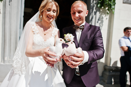 Wedding couple with pigeons at hands against church gate.の写真素材