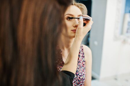 Make up artist makes morning make up for bride at beauty salon.