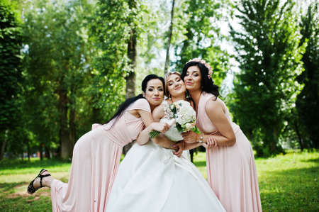 Bride posed on park with two cute brunette bridesmaids on pink dresses.の写真素材