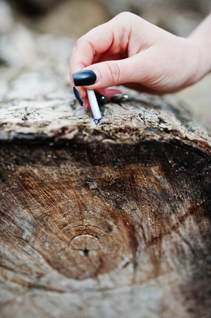 Hand of girl with extinguished cigarette on stump. Stop smoking social problem.の写真素材