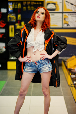 Red haired model posed weared on working jacket at store or household shop of working tools.の写真素材