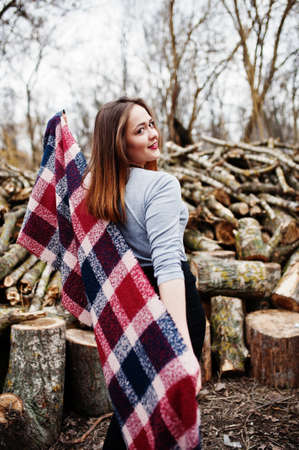 Young hipster girl wear on blanket against wooden stumps on wood.の写真素材