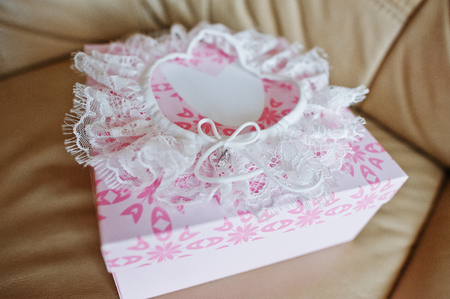 White wedding garter on rose box at leather sofa.の写真素材