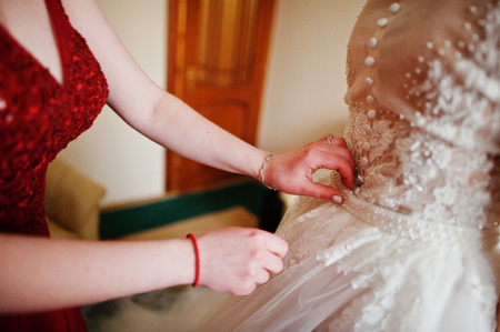 Bridesmaid helped wear wedding dress for bride.の写真素材