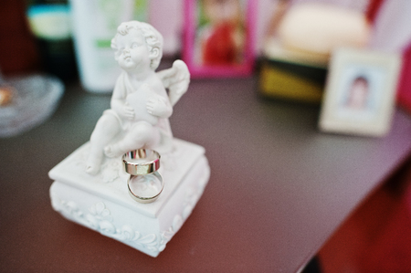 Two white gold wedding rings at angel figurine.の写真素材