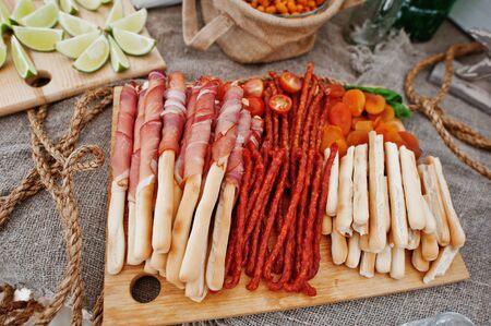 Salted sticks with ham and Bavarian sausages on wooden board at catering wedding.の写真素材