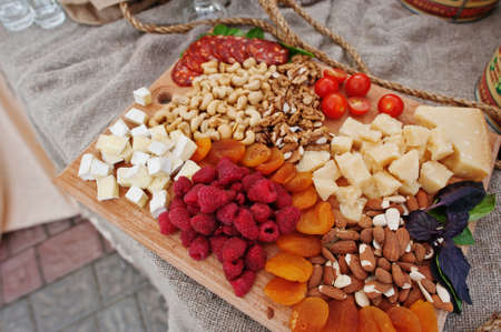 Raspberry, cheese and different nuts on wooden board at wedding catering table.の写真素材