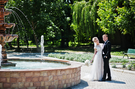 Stylish and gorgeous wedding couple walking outdoor near fountain.の写真素材