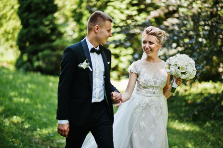 Stylish and gorgeous wedding couple walking outdoor at park on sunny weather.の写真素材