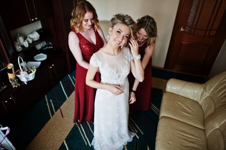 Bridesmaids helped wear bride dress in wedding morning.の写真素材