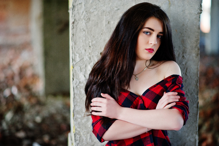 Portrait girl with red lips wearing a red checkered shirt with bare shoulders posed sexy background abadoned place.の写真素材