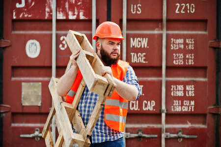 Brutal beard worker man suit construction worker in safety orange helmet with pallet.の写真素材