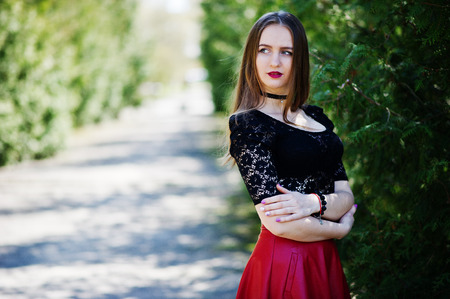 Portrait of girl with bright make up with red lips, black choker necklace on her neck and red leather skirt.の写真素材