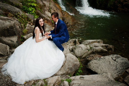 Lovely wedding couple against waterfall on sunset at Carpathian mountains.の写真素材