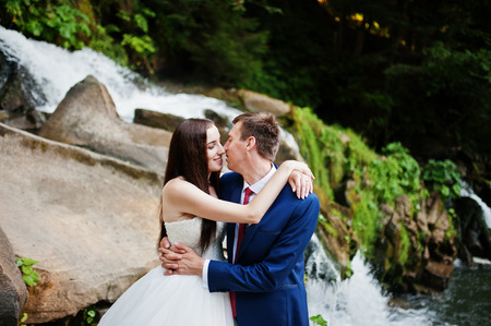 Lovely wedding couple against waterfall on sunset at Carpathian mountains.の写真素材