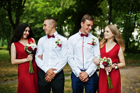 Bridesmaids at red dresses with groomsman or best man at wedding.の写真素材