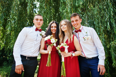 Bridesmaids at red dresses with groomsman or best man at wedding.の写真素材