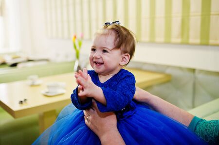 Cute little baby girl at blue dress at hands of mother.の写真素材