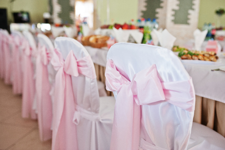 Chairs with pink bow at wedding hall.の写真素材