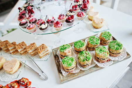Table catering with different cakes and cupcakes at wedding reception.