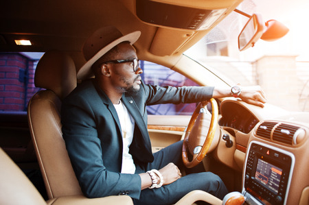 Stylish black man sitting behind the wheel of luxury car. Rich african american businessman.の写真素材