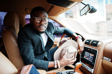 Stylish black man sitting behind the wheel of luxury car. Rich african american businessman.の写真素材