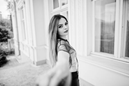 Fashionable woman look at white shirt, black transparent clothes, leather pants, posing at street. Concept of fashion girl, follow me theme.の写真素材