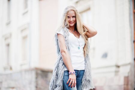 Stylish blonde woman wear at jeans and girl sleeveless with white shirt against street. Fashion urban model portrait.の写真素材